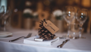 Pine cone favor sitting on a linen napkin with a groom tag